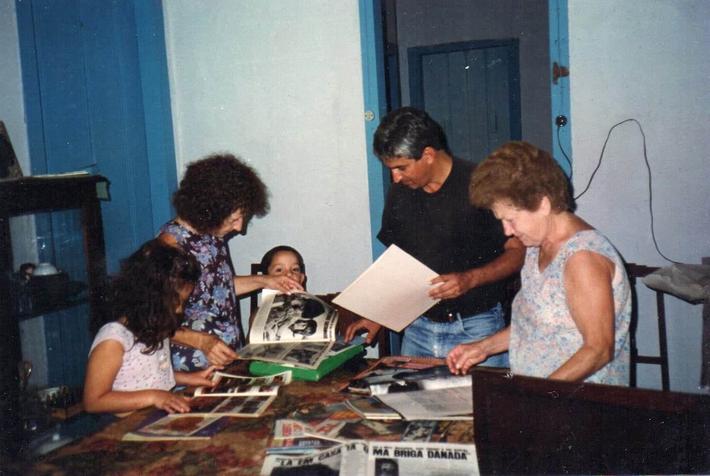 A imagem mostra Gercy e Maria Leonôr mostrando o acervo de revistas a dois sobrinhos e a um jornalista.